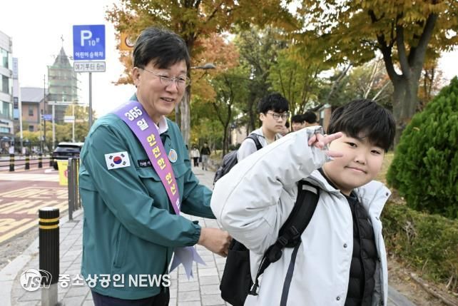 이민근 안산시장(사진 왼쪽)이 학현초등학교 앞에서 ‘스쿨존 어린이 교통안전 캠페인’을 진행하며 등교하는 어린이의 가방에 '홍이 키링'을 달아주고 있다.